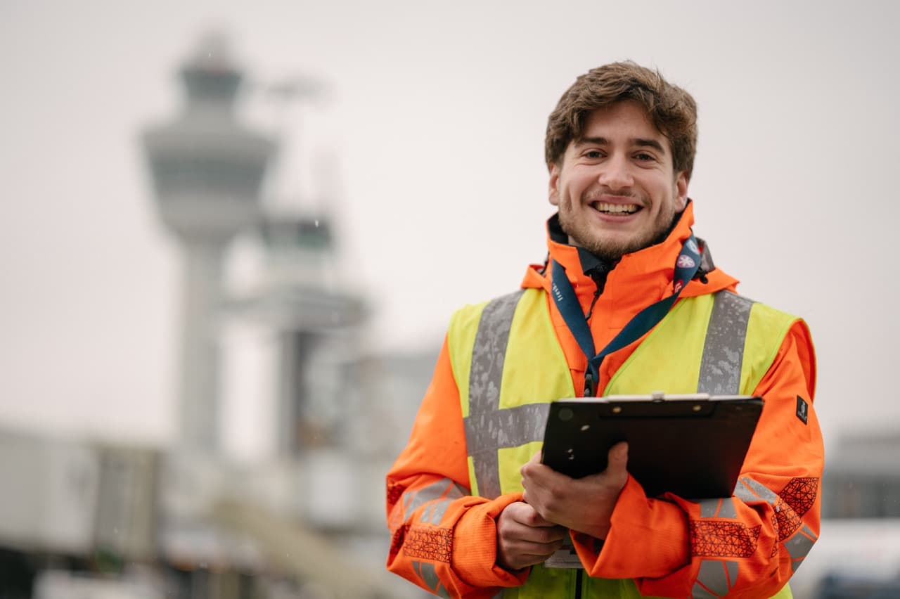 Employee holding forms in front of Schiphol Tower